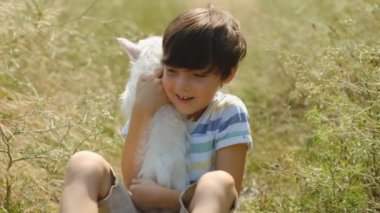 Köpeği olan bir çocuğun arkadaşlığı. Kollarında West Highland White Terrier köpeği tutan mutlu çocuk. Çocuk yazın köpek yavrusuyla parkta yürür. Çocuğun doğadaki en sevdiği köpek..