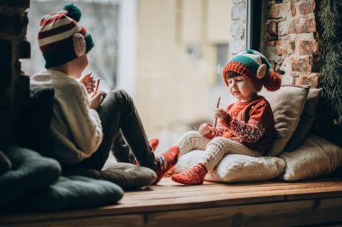 İki küçük kardeş pencerenin yanında oturup Noel Baba 'yı ve Noel Baba' yı bekliyorlar. Mutlu çocukluklar ve Noel.