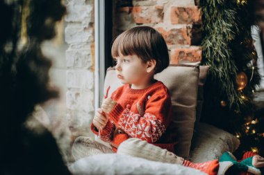 Çocuk pencerede oturur ve Noel Baba 'yı bekler. Noel tatilini bekliyorum. Mutlu bir çocukluk. İtfaiyecileri bekliyoruz..