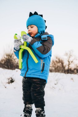 Noel tatilleri. Çocuk kışın parkta karla oynuyor. Çocuklarla aktif kış yürüyüşleri.
