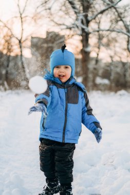 Noel tatilleri. Çocuk kışın parkta karla oynuyor. Çocuklarla aktif kış yürüyüşleri.