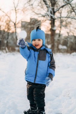 Noel tatilleri. Çocuk kışın parkta karla oynuyor. Çocuklarla aktif kış yürüyüşleri.