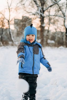 Noel tatilleri. Çocuk kışın parkta karla oynuyor. Çocuklarla aktif kış yürüyüşleri.