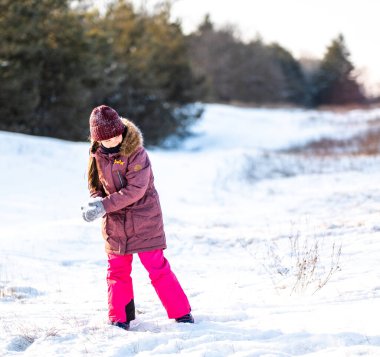 Kışın aktif aile tatili. Anne ve kızı izin günlerinde ormanda eğlenirler. Annesiyle parktaki karda oynayan bir kız..