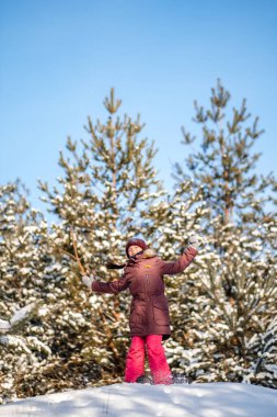 Sağlıklı bir yaşam tarzı. Aktif çocuk. Mutlu noeller. Kış parkında yürüyüş yapan bir kız. Karlı bir parkta zıplayan genç kız..