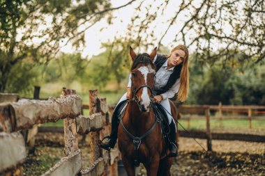 A young female jockey is sitting on her horse in show jumping training. Preparing for the competition. Love for horses.