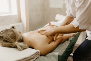 Professional doctor physiotherapist makes a back massage to a young woman. Therapeutic massage in the physiotherapist's office.