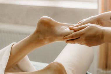 Professional doctor physiotherapist makes a foot massage to a young woman. Therapeutic massage in the physiotherapist's office.