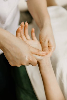 Professional manual therapist makes the hands of a young woman. Treatment of muscles and joints of the hands.