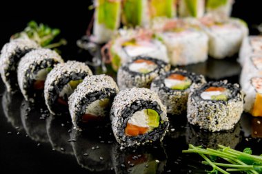 Sushi set on a black background. Fresh variety of rolls in a Japanese restaurant. Eastern cuisine.