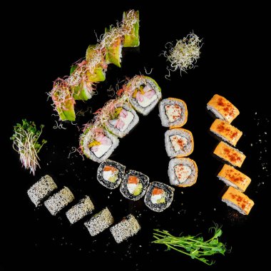 Sushi set on black background top view. Assortment of fresh mouth-watering sushi in an oriental restaurant.