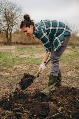 Bir kadın tarlada toprağı kazıyor. İlkbaharda tarımda tarım işi. Baharda koyun ekmek için toprağı hazırlıyorum..