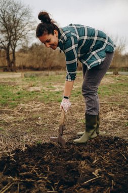 Bir kadın tarlada toprağı kazıyor. İlkbaharda tarımda tarım işi. Baharda koyun ekmek için toprağı hazırlıyorum..