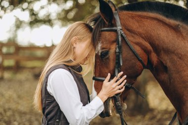 Genç bir dişi binici atının yanında duruyor ve bir yarışa hazırlanıyor. Atlama eğitimini göster. Atları severim..