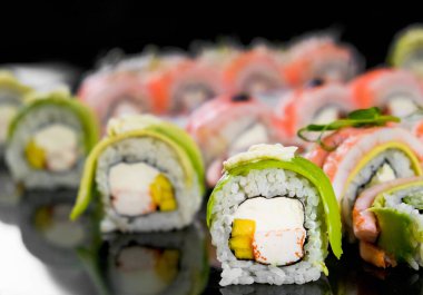 Suşi siyah arka planda. Bir Japon restoranında taze ekmek çeşitleri. Doğu mutfağı.