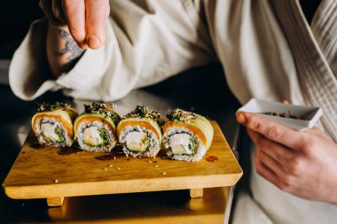 Suşi ustası taze iştah açıcı suşi yapar. Ekmeğin üstüne susam tohumları serpin..