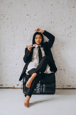 Koyu tenli genç bir kadın beyaz bir odada iddialı bir şekilde oturur ve yemek çubuklarıyla suşi yer. Takım elbiseli Afrikalı Amerikalı kadın rulo yiyor..