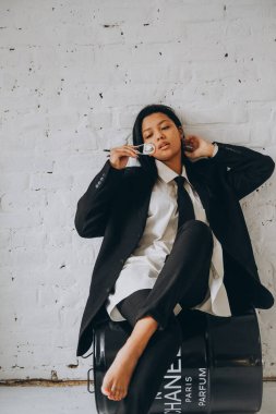 Koyu tenli genç bir kadın beyaz bir odada iddialı bir şekilde oturur ve yemek çubuklarıyla suşi yer. Takım elbiseli Afrikalı Amerikalı kadın rulo yiyor..