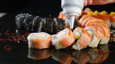 Şef bir Japon restoranında suşinin üzerine sos döker. Geleneksel Japon yemeklerinin profesyonel hazırlığı - suşi.