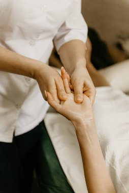 Professional manual therapist makes the hands of a young woman. Treatment of muscles and joints of the hands.