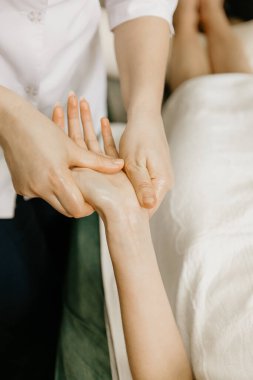 Professional manual therapist makes the hands of a young woman. Treatment of muscles and joints of the hands.