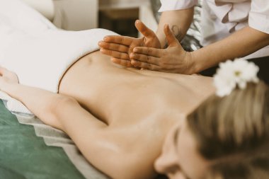 Professional doctor physiotherapist makes a back massage to a young woman. Therapeutic massage in the physiotherapist's office.