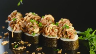 Profesyonel bir Asyalı şef geleneksel suşi hazırlar. Şef sushi 'yi bitki ve susam tohumlarıyla süslüyor..