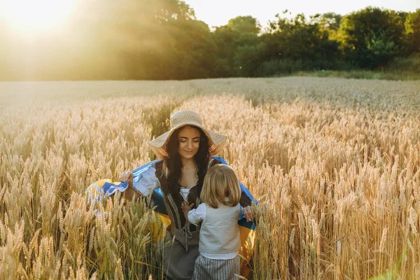 stock image A young woman with a baby walk in a wheat field in the summer with the flag of Ukraine. Ukraine's victory in the war against Russia. Ukraine will win.