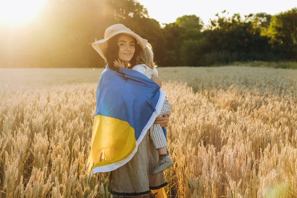 一个带着孩子的年轻女人拿着乌克兰国旗在麦田里散步 乌克兰在对俄战争中的胜利 乌克兰会赢 — 图库照片