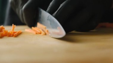 Mutfaktaki tahta bir tahtanın üzerinde havuç dilimlemek. Sebze kesmek, yemek yapmak..