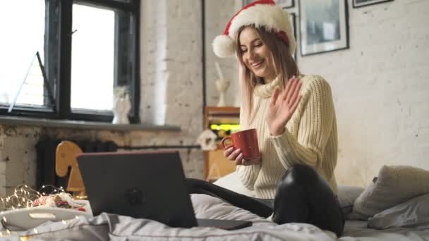 若い女性は彼女の家族や友人に休日にメリークリスマスを望んでいます クリスマスにリモートインターネット通信 — ストック動画