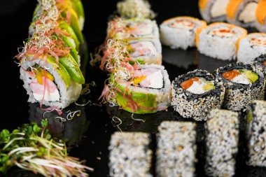Sushi set on a black background. Fresh variety of rolls in a Japanese restaurant. Eastern cuisine.