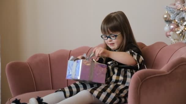 Flicka Med Downs Syndrom Sitter Soffa Vardagsrummet Och Öppnar Julklapp — Stockvideo