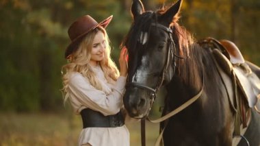 Genç ve güzel bir kadın sonbahar ormanında bir atın üzerinde oturuyor. Ata binmek. Bir gösteri atlama yarışmasına hazırlanılıyor.