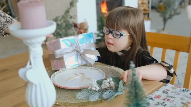 증후군이있는 소녀는 크리스마스 선물을 상자를 흔들며 무엇을 추측하려고합니다 — 비디오