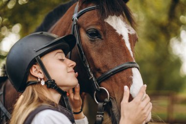 Genç bir dişi binici atının yanında duruyor ve bir yarışa hazırlanıyor. Atlama eğitimini göster. Atları severim..