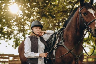 Genç bir dişi binici atının yanında duruyor ve bir yarışa hazırlanıyor. Atlama eğitimini göster. Atları severim..