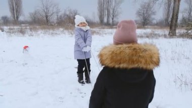 Kızıyla birlikte genç bir kadın kışın parkta oynar. Çocuklarla kış tatili. Kaydırma.