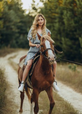 Genç ve güzel bir kadın sonbaharda ormanda ata biner. Sonbaharda akşamları ata binmek. At yarışı sporu için çiftlikte at yetiştiriyorum..