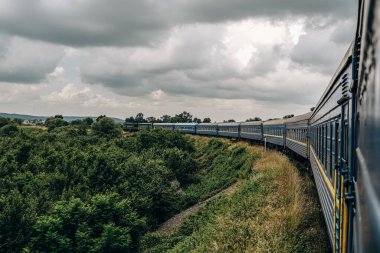 Yazın trenle dağlara seyahat et. Tren penceresinden manzara çok güzel. Yaz tatili dağlarda.