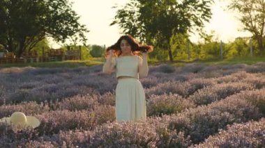 Genç, güzel, esmer bir kadın yazın gün batımında açan lavanta tarlasında yürüyor..