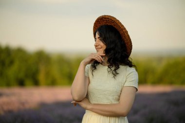 Genç, güzel, esmer bir kadın yazın gün batımında açan lavanta tarlasında yürüyor..