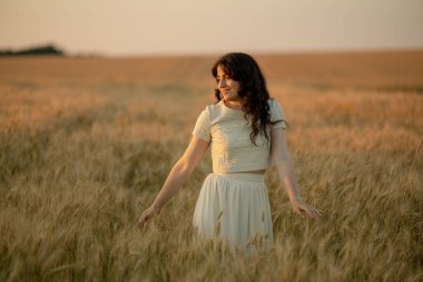 Genç bir esmer yazın günbatımında buğday tarlalarında yürür. Organik buğday ve arpa yetiştiriyor..