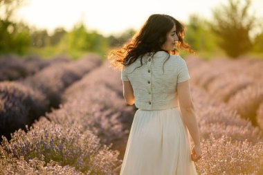 Genç bir esmer yazın günbatımında buğday tarlalarında yürür. Organik buğday ve arpa yetiştiriyor..