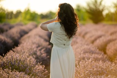 Genç bir esmer yazın günbatımında buğday tarlalarında yürür. Organik buğday ve arpa yetiştiriyor..