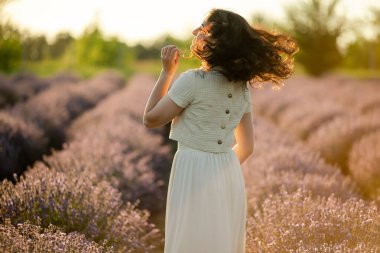Genç bir esmer yazın günbatımında buğday tarlalarında yürür. Organik buğday ve arpa yetiştiriyor..