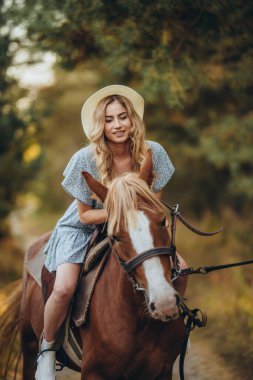 Genç ve güzel bir kadın sonbaharda ormanda ata biner. Sonbaharda akşamları ata binmek. At yarışı sporu için çiftlikte at yetiştiriyorum..