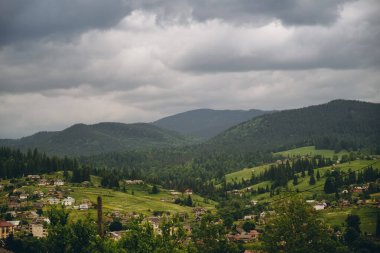 Yazın kozalaklı bir ormanın arka planına karşı bir dağ köyünün manzarası. Yazın dağlara seyahat. Yazın otantik bir dağ köyünde yaz tatili.