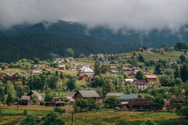 Yazın kozalaklı bir ormanın arka planına karşı bir dağ köyünün manzarası. Yazın dağlara seyahat. Yazın otantik bir dağ köyünde yaz tatili.