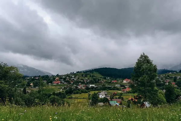 Yazın kozalaklı bir ormanın arka planına karşı bir dağ köyünün manzarası. Yazın dağlara seyahat. Yazın otantik bir dağ köyünde yaz tatili.